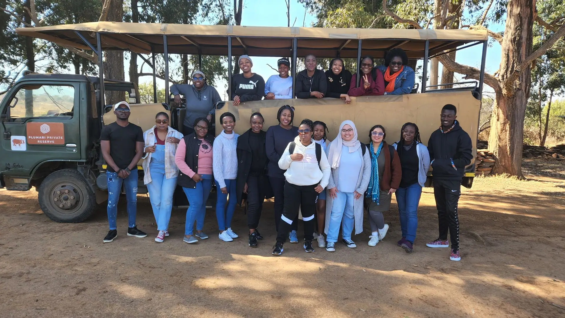 Cohort group photo beside a safari vehicle