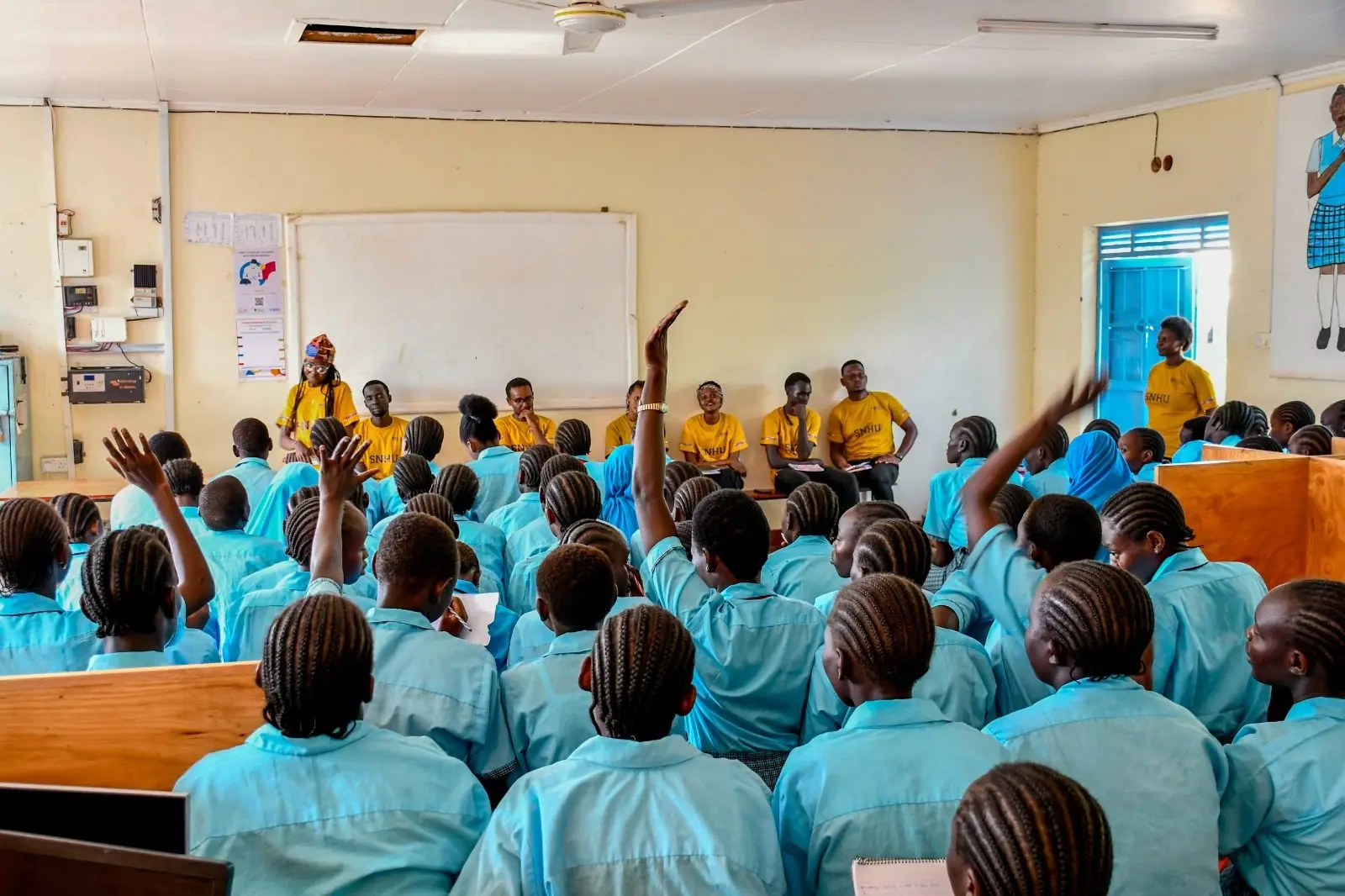 Hall of learners raising their hands during a session