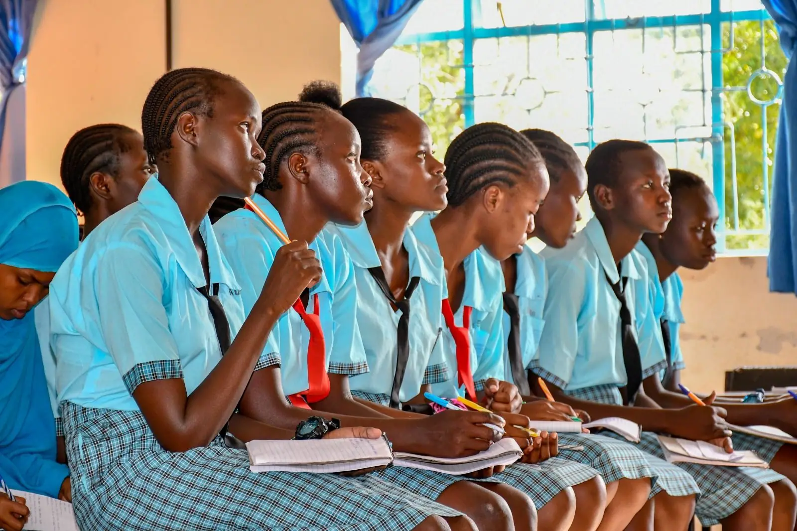 Learners in blue uniforms taking notes