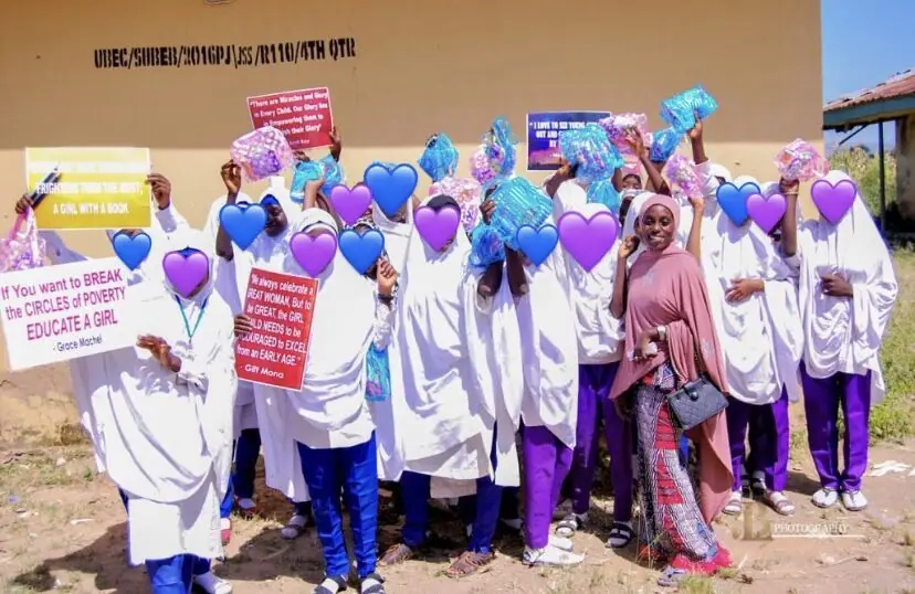 Schoolgirls holding purple balloons and campaign signs