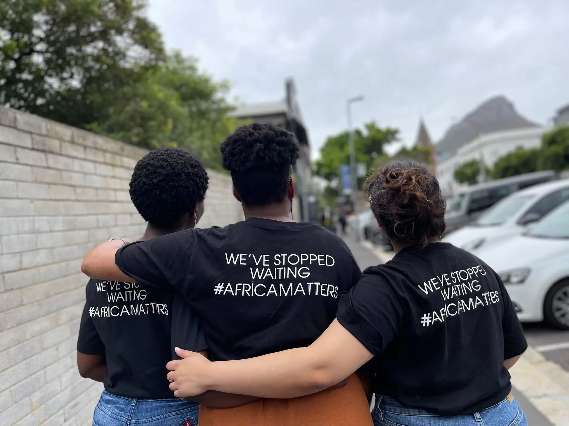 Three friends showing the backs of their #AfricaMatters T-shirts